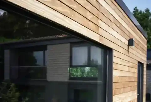 Großes, bodenebenes Außenfenster an einer hellen Holzfassade.