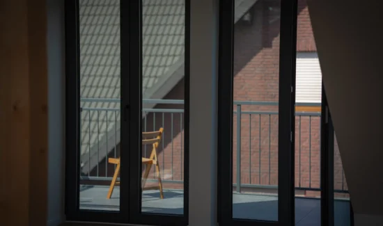 Zwei zweigeteilte Balkonfenstertüren mit schwarzem Rahmen im Innenbereich.